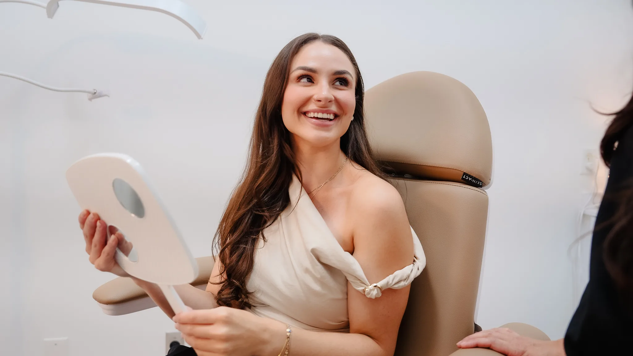 Client reviewing her skin in a hand mirror after treatment
